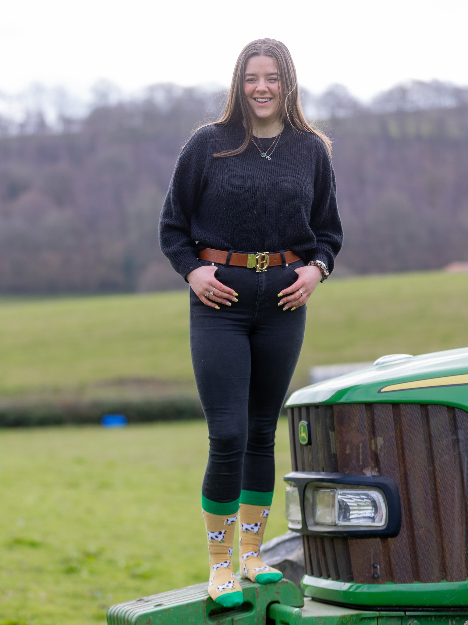 cow socks in a crew style with black and white cows wearing green wellies on a mustard coloured background with dark green top, heel and toe