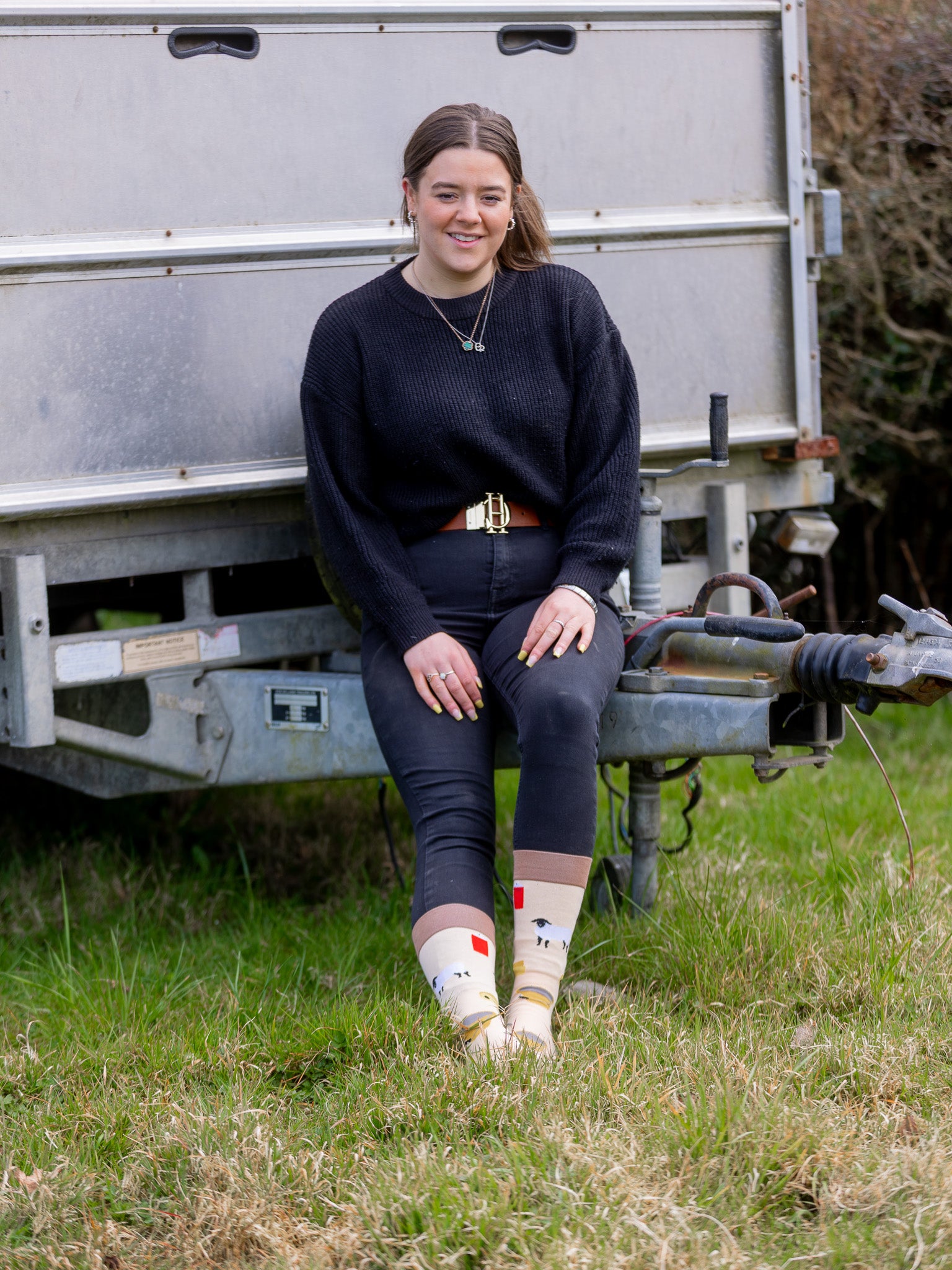 Sheep socks. A unique design with lots of sheep features all over, including a yellow sheep identification tag, grey shears, yellow bucket of feed, Suffolk sheep and a red spray can. These are all on a light peach background with a brown top, heel and toe.