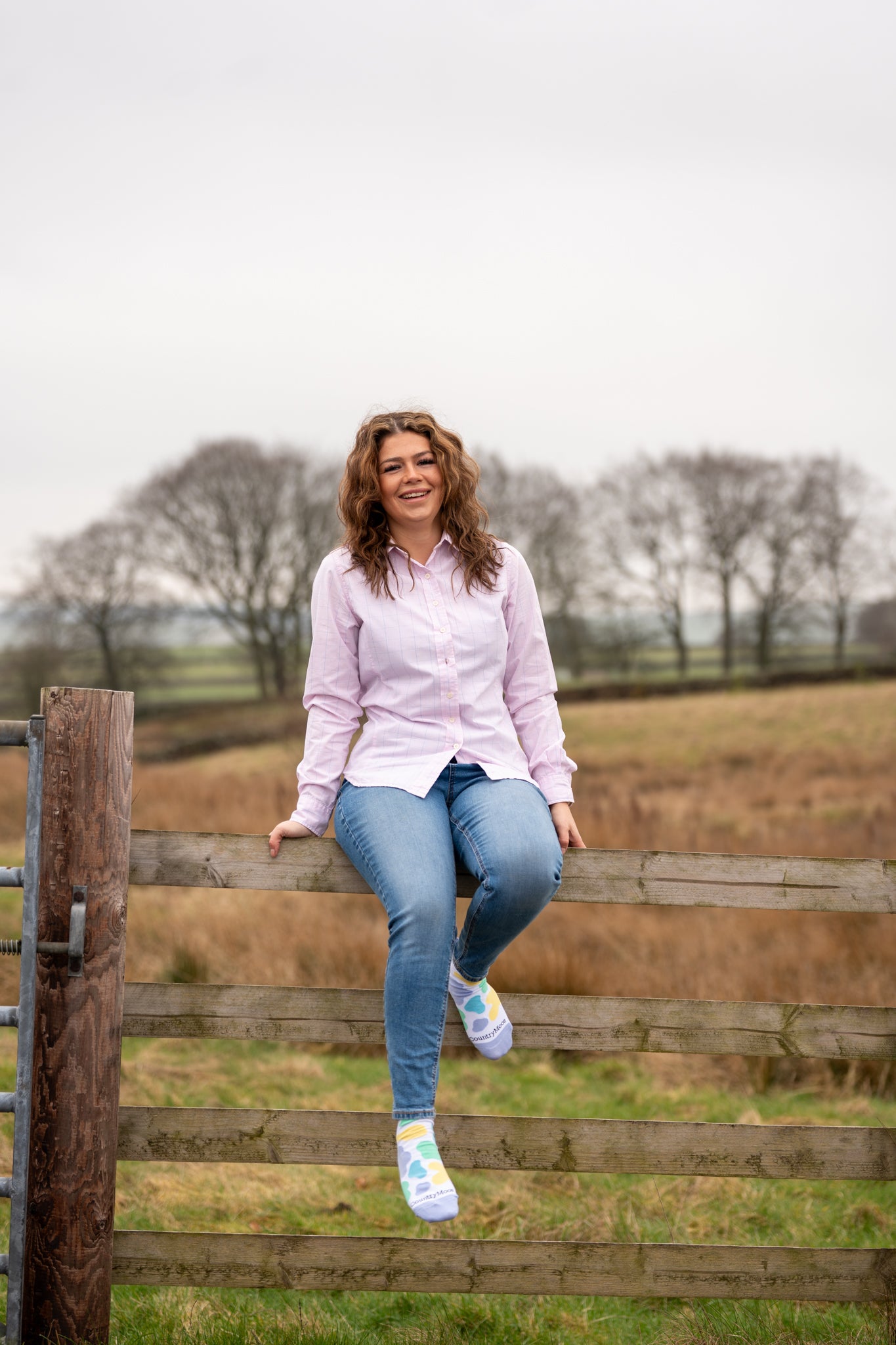 Country farm girl sat on fence wearing mix cow print ankle socks