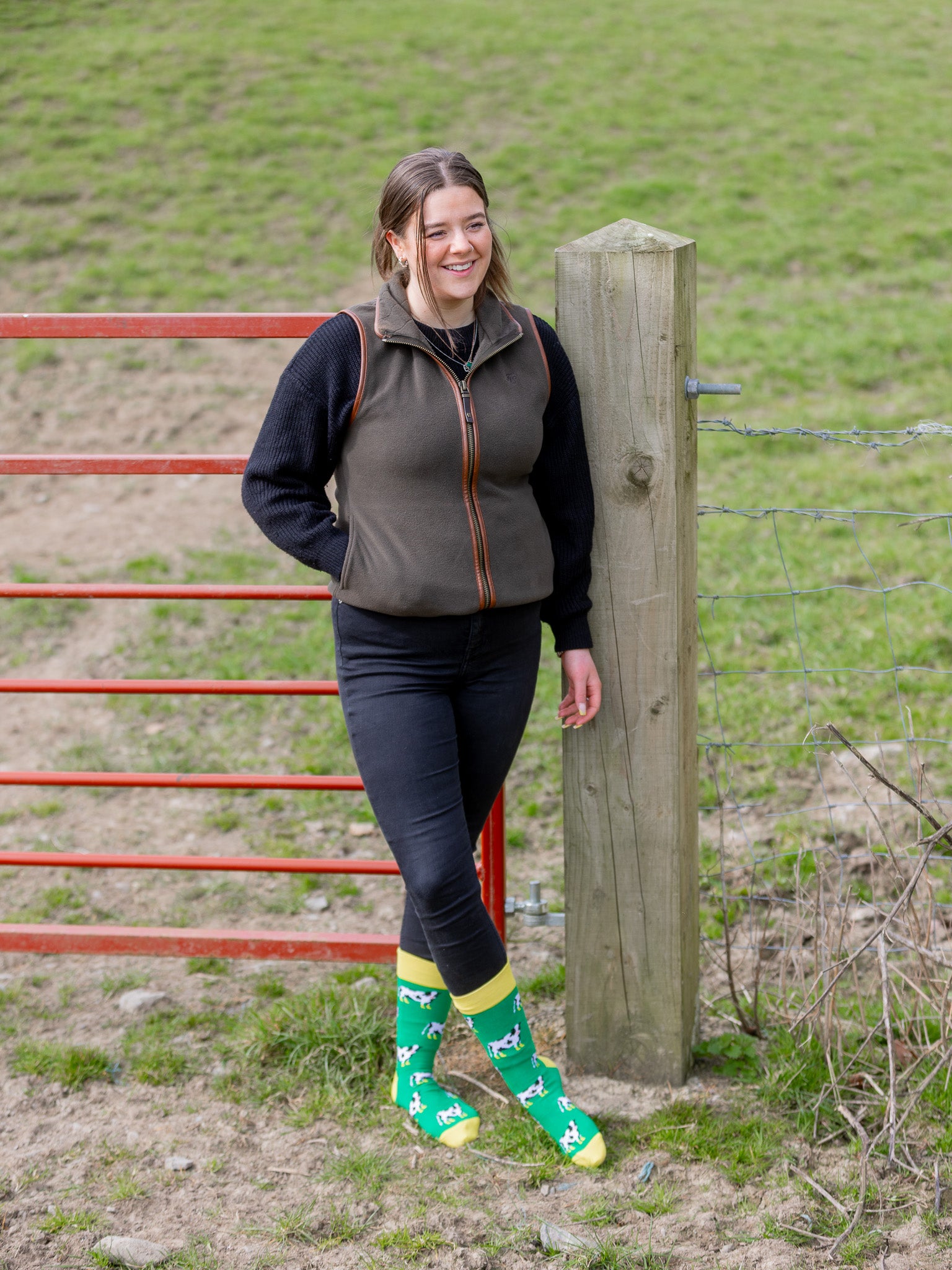 Cow socks with black and white cows wearing yellow wellies as part of the charity yellow wellies. The crew socks are vibrant with a grass green background and a bright yellow top, heel and toe.