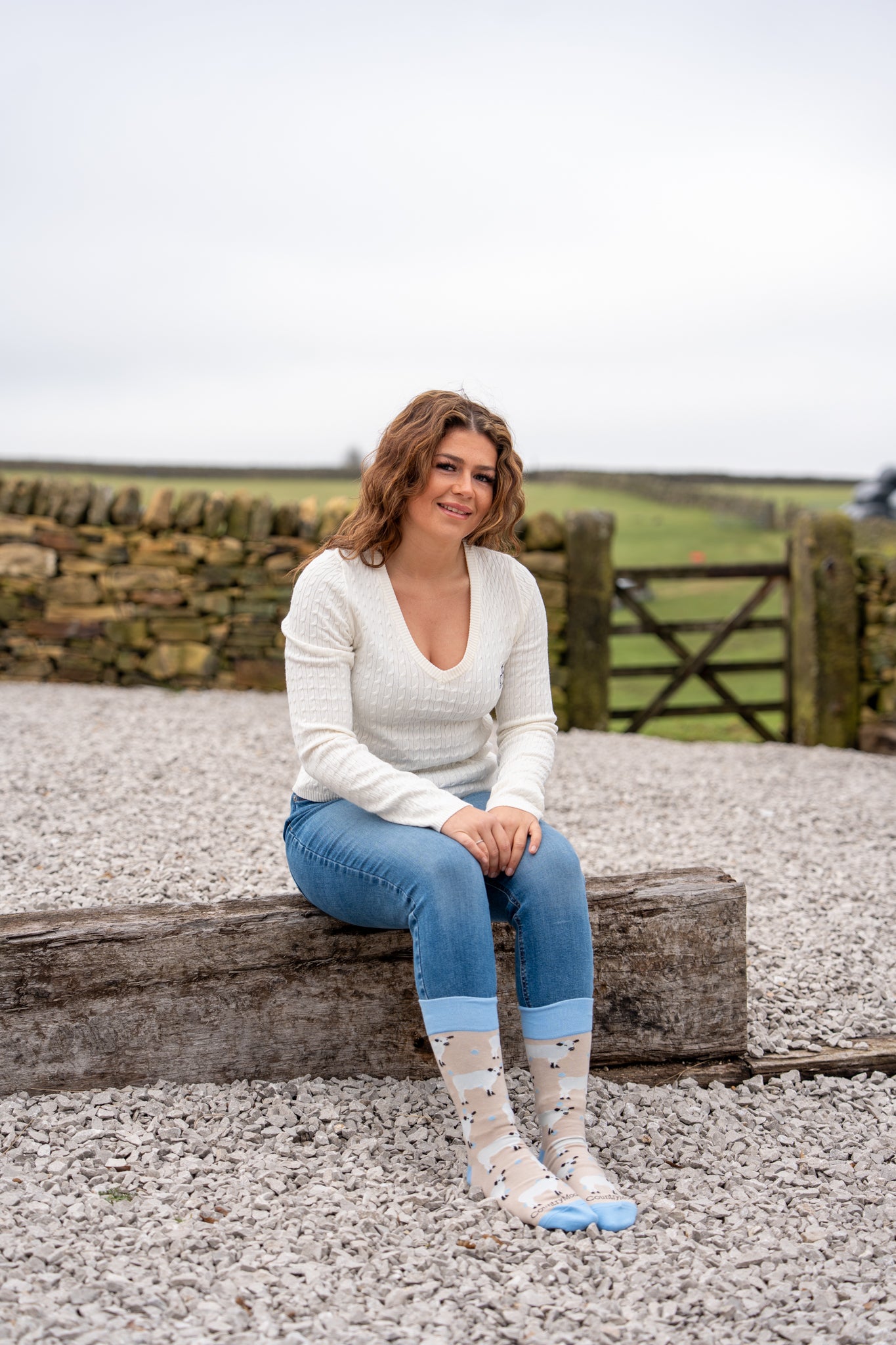 model sat down wearing blue cow crew socks