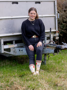 Sheep socks. A unique design with lots of sheep features all over, including a yellow sheep identification tag, grey shears, yellow bucket of feed, Suffolk sheep and a red spray can. These are all on a light peach background with a brown top, heel and toe.