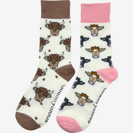 2 pairs of crew socks featuring a pink cow design on a light cream background, showcasing elegant brown and black cows with an elegantly matched pink top, heel, and toe. Also included are Highland cow socks, set against a cream backdrop adorned with playful brown highland cows and brown polka dots, complemented by matching brown tops, heels, and toes. Perfect gifts for countryside enthusiasts, outdoor lovers and farming people, these cozy socks bring a touch of country style and comfort to any wardrobe.