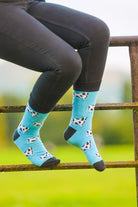Dairy cow crew socks. A unisex design, these cosy cow socks have black and white cows on a sky blue background with a black top, heel and toe. 
