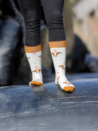 Happy Birthday cow socks. These crew socks are sporting brown cows with colourful party hats on a cream background and a brown top, heel and toe. 