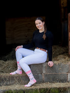 Pink themed cow socks with black and white cows sporting a rose in their mouths on a light pink background and vibrant top, heel and toe. 