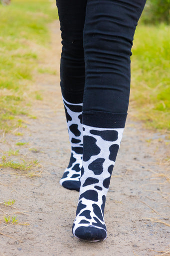 Black and white cow print socks showcasing a fun and trendy design inspired by classic cow patterns. Perfect for animal lovers, these stylish socks combine comfort and flair, making them ideal for everyday wear or adding a unique touch to your country outfit. Elevate your sock game with these chic cow print socks.