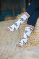 Highland cow socks set against a cream background, adorned with charming brown top heel and toe accents and playful polka dots. Featuring delightful Highland cows, these cozy socks are perfect for adding a touch to your country style wardrobe while ensuring comfort for everyday wear.