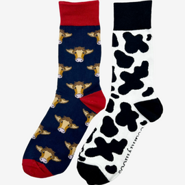 2 pairs of crew socks featuring a navy red cow design on a navy background, showcasing elegant brown cows with an elegant royal red top, heel, and toe. Also included are cow print socks, set against a white backdrop adorned with playful black cow print, complemented by black tops, heels, and toes. Perfect gifts for countryside enthusiasts, outdoor lovers and farming people, these cozy socks bring a touch of country style and comfort.