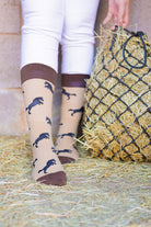 Elegant brown-themed horse socks featuring a stylish design of black rearing horses on a light brown background. The socks are accented with a more vibrant brown top, heel, and toe for added sophistication. Perfect for equestrian enthusiasts and horse lovers, these comfortable socks combine practicality with a chic country aesthetic, making them a great addition to any wardrobe and a lovely gift for those who appreciate the beauty of horses.