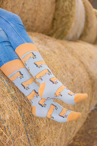 Jersey cow socks featuring adorable Jersey cow illustrations on a light brown background, with a slightly darker brown accent on the top, heel, and toe. These comfy country and stylish country style socks are perfect for cow and animal fans, adding a fun and unique touch to your outfit while celebrating the countryside and the outdoors.