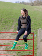 Charity cow socks with black and white cows wearing yellow wellies on a grass green background and a bright yellow top, heel and toe. 