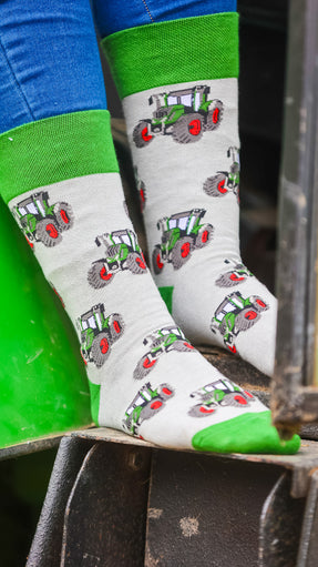 "These charming green tractor socks showcase a vibrant tractor design against a grey background, with matching green heel and toe accents. Ideal for completing a country outfit, they offer a touch of rustic style and comfort for your journeys around the farm. Celebrate your love for rural life with these stylish and cozy socks!"