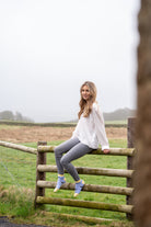 Country girl sitting on a fence in purple friesian cow ankle socks 