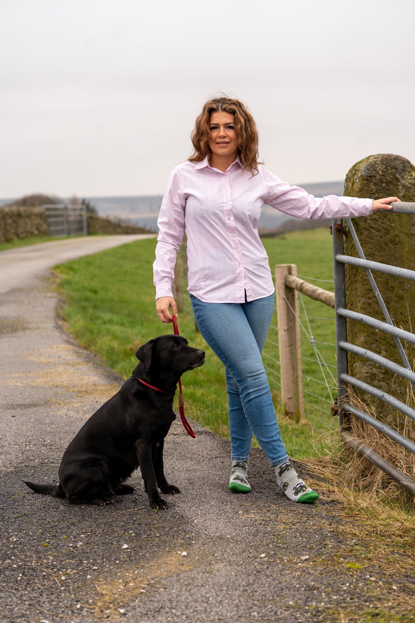 Country girl stood with her dog modelling green tractor ankle socks 