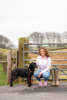Country lady sat with dog wearing pink friesian cow ankle socks 