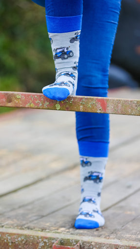 Blue country-style tractor socks featuring a modern tractor design on a grey background, accented with a matching blue top, heel, and toe. These cozy and stylish socks are perfect for farmers and tractor enthusiasts who love the countryside, offering both comfort and a touch of country charm for everyday wear.