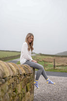Girl sitting on wall wearing purple friesian cow ankle socks 