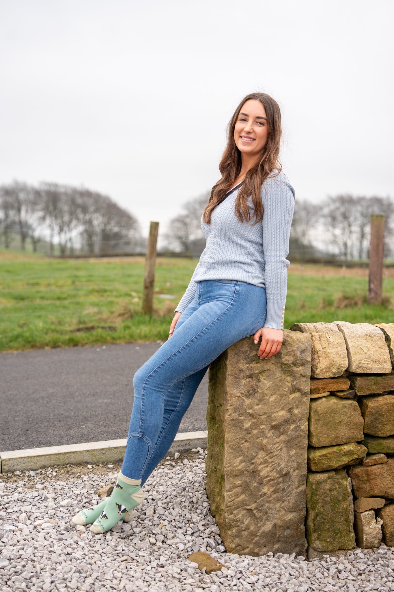country girl sat on wall wearing green cow ankle socks