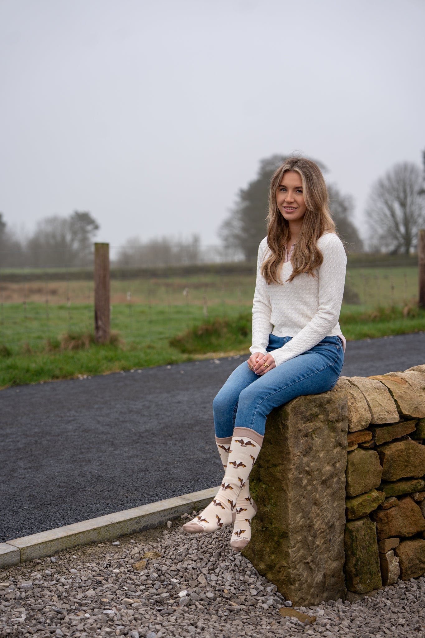 country girl sat wearing extra long friesian cow welly socks 